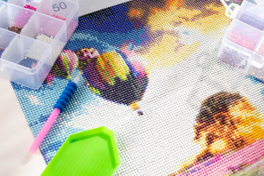 Close-up of a diamond painting and the tools needed to assemble it. Art therapy concept.