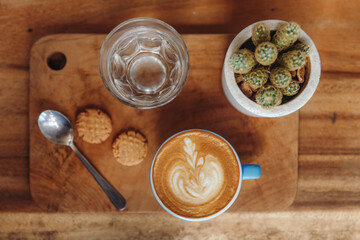 Hot Art Latte Coffee and Glass of Water on the Table, Coffee Shop Background, Warm Tone