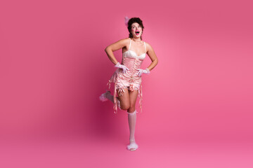 A young woman in a pink corset dress poses against a vibrant pink background, blending modern fashion with classic glamour