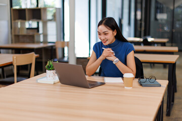Asian professional business woman office worker analyst sitting at desk working on laptop thinking on project plan, analyzing marketing or financial data online, watching elearning webinar.	