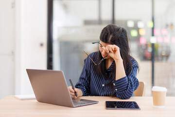 Portrait of tired young business Asian woman work with documents tax laptop computer in office....