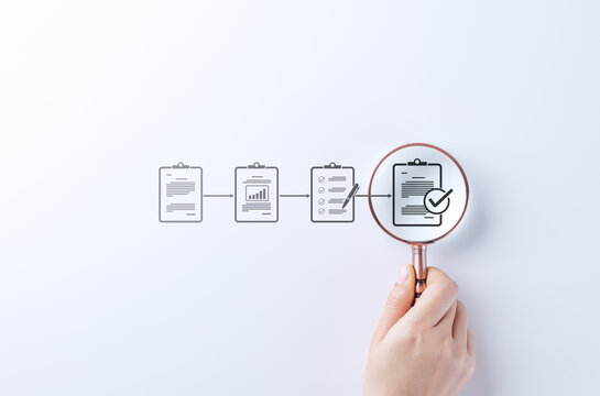 Document review and quality control process. A hand holding magnifying glass focuses on completed checklist in document workflow, symbolizing quality control, verification, and approval. Certificate,
