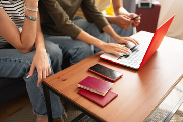 Women friends planning a trip with the computer on the living room. Using passports, a smartphone and a credit card