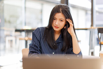 Fototapeta premium Portrait of tired young business Asian woman work with documents tax laptop computer in office. Sad, unhappy, Worried, Depression, or employee life stress concept
