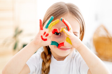 The child draws at home. Paint on the hands. Decorative and applied art for children. A little girl draws a bright picture. A creative child plays and learns.