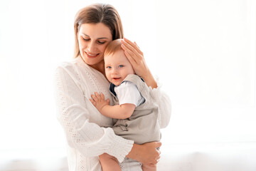 a mother with a child, a young mother gently hugs and kisses her little son at home on a white isolated background, maternal love and care, a happy decree, a mother and a little boy, a place for text