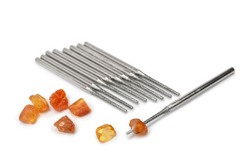 Mini diamond drills and pieces of natural amber stones with holes drilled for jewelry making