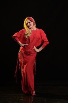 Young woman belly dancer in a red oriental costume on a black background