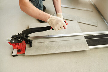 A close-up of the hands of a master who divides time into two parts using a machine. An installation for cutting large ceramic tiles into smaller ones with precise dimensions. High quality photo