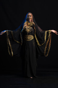 woman with long hair in oriental dancer costume posing and dancing on a black background