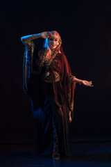 woman with long hair in oriental dancer costume posing and dancing on a black background