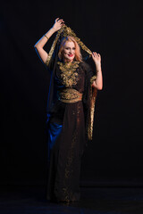 girl with long hair in oriental dancer costume posing and dancing on a black backgroun