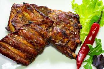 Juicy grilled ribs served with fresh greens and chili peppers