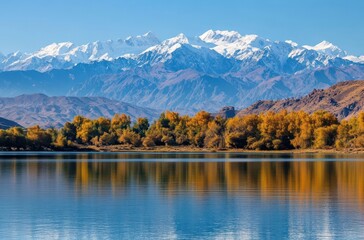 Obraz premium Breathtaking Mountain Landscape with Snow-Capped Peaks and Serene Lake Reflections Under Clear Blue Sky in Autumn Season