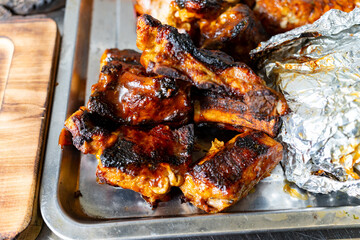 Grilled ribs served on a silver platter with foil-wrapped side