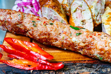 Delicious grilled sausage with colorful peppers on a wooden board