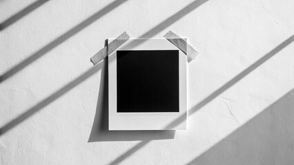 Isolated Polaroid photo card with a blank, dark space, secured with masking tape against a neutral background, ideal for placeholders or text