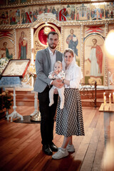 Obraz premium a family with children in an Orthodox Christian church or temple are praying or have come to the sacrament of baptism, believers in a holy place, introducing children to the faith