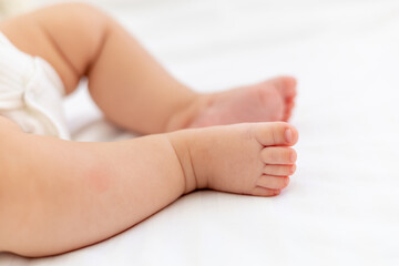 baby's small feet on a white bed, a place for text, a close-up of a little baby's feet