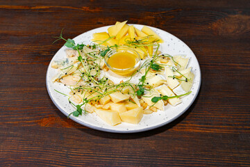 Gourmet cheese platter with honey and fresh fruits at dinner