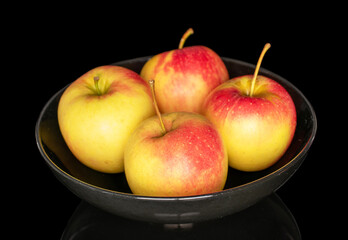 Several ripe apples on a ceramic plate, close-up, isolated on a black background.