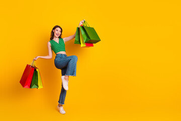 Young Woman Shopping with Bright Smiley Expression and Colorful Bags Against Yellow Background