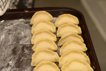 Homemade dumplings arranged meticulously on a wooden tray ready for cooking