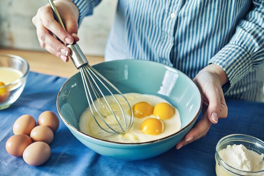Baking Preparation: Whisking Eggs in a Blue Bowl for a Recipe - Powered by Adobe