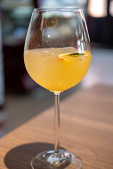 A glass of citrus sangria, featuring a vibrant orange hue with ice and a slice of fruit garnish