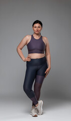 Obraz premium Plus size woman in gym clothes on grey background