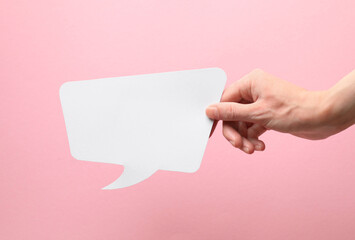Obraz premium Woman holding blank speech bubble on light pink background, closeup. Space for text