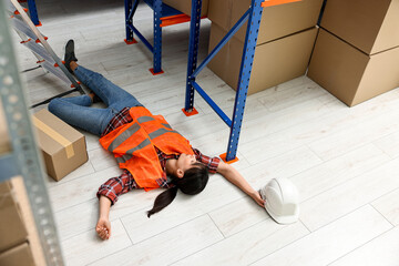 Accident at work. Unconscious woman lying on floor in warehouse