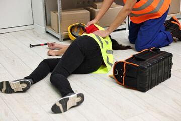 Accident at work. Man helping his unconscious colleague in warehouse