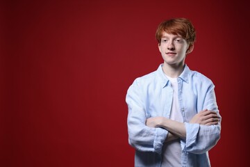 Teenage boy with freckles on dark red background. Space for text