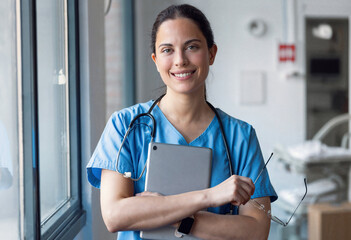 Female nurse using her digital tablet while looking in the consultation