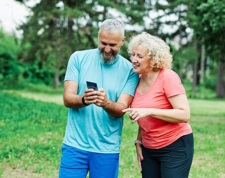 man woman outdoor retirement couple phone mobile smartphone  mid adult middle age middle aged mature active park old using internet smart phone mature cell performance app