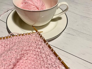 Process of knitting craft handmade hobby clew and needles and a cup 