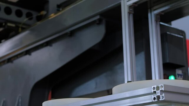 White polypropylene yogurt containers are transferred by an automated pick and place robotic arm with suction cups: plastic injection molding process at factory or production plant - close up