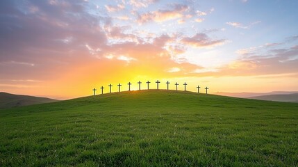 Fototapeta premium Silhouetted crosses standing on a grassy hill against a beautiful glowing sunset sky with dramatic clouds