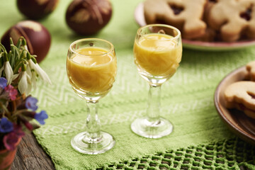 Two shot glasses of Eiecognac with Easter eggs and spring flowers on a table
