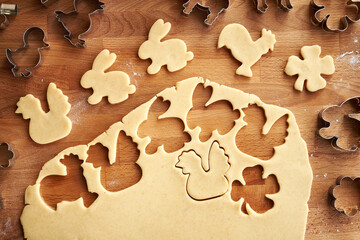 Cutting out bunny and chicken shapes from raw pastry dough - preparation of homemade Linzer Easter cookies