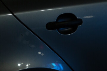 A detailed closeup image showing a car door handle, elegantly positioned in the darkness, highlighting its sleek design features