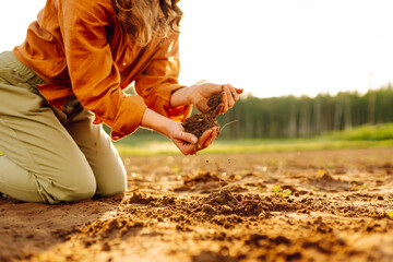 Close-up of farmer's hands holding fertile soil. Young female agronomist checking soil quality...