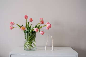 A beautiful bouquet of pink tulips beside candles enhance home decor and ambiance.