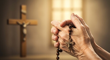 Hands holding a rosary with a crucifix, in front of a blurred wooden cross.