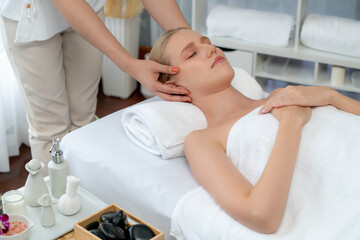 Fototapeta premium Caucasian woman enjoying relaxing anti-stress head massage and pampering facial beauty skin recreation leisure in dayspa modern light ambient at luxury resort or hotel spa salon. Quiescent