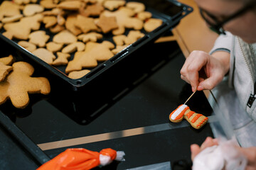 Confectioner uses a toothpick to apply a pattern of icing to a cookie