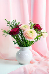 Eine edle keramische Vase mit Rapunzeln vor einer Wand mit Vorhang