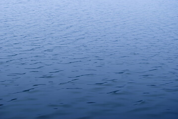 Calm blue color water surface with fog above the horizon