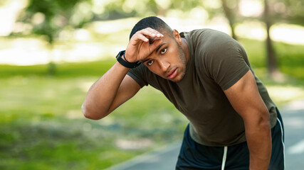 Naklejka premium Athletic black guy feeling tired after his morning run at urban park, panorama